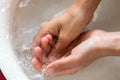 ChildÃ¢â¬â¢s hands under white bowl with water upon water stream Royalty Free Stock Photo